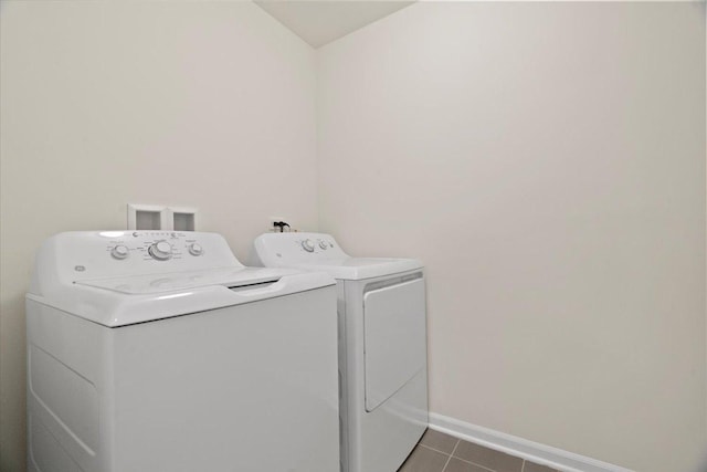 washroom with laundry area, baseboards, washer and clothes dryer, and dark tile patterned flooring