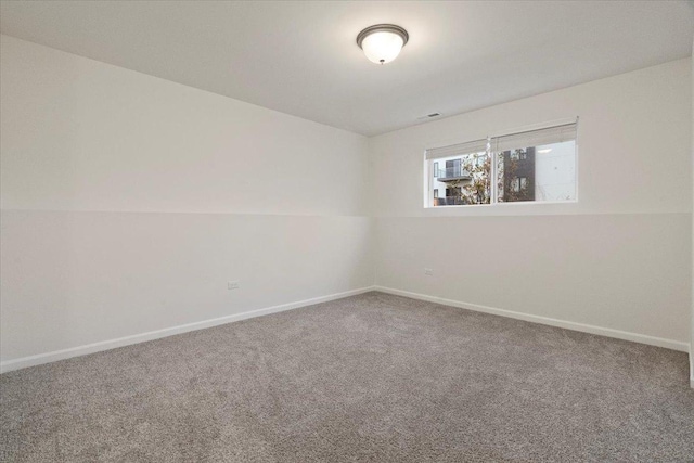 unfurnished room with carpet floors, visible vents, and baseboards