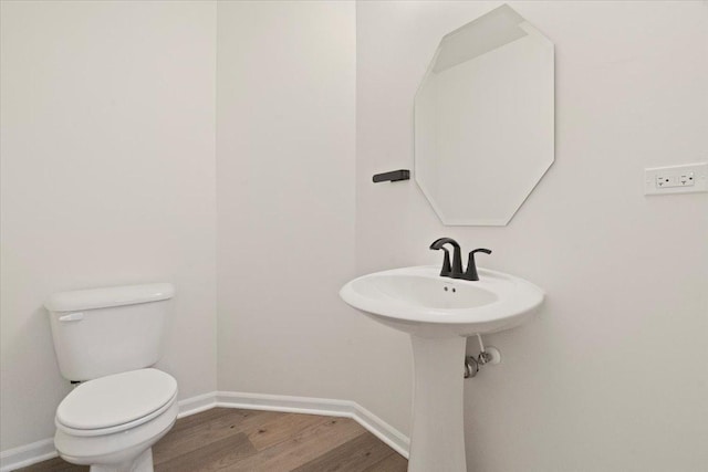 half bathroom featuring baseboards, toilet, and wood finished floors