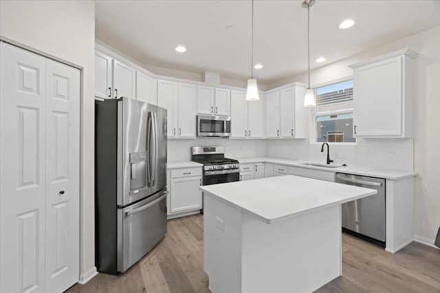 kitchen with stainless steel appliances, backsplash, light wood-style flooring, white cabinetry, and a sink