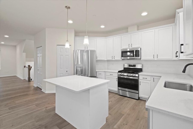 kitchen featuring light wood-style floors, decorative backsplash, stainless steel appliances, and a sink