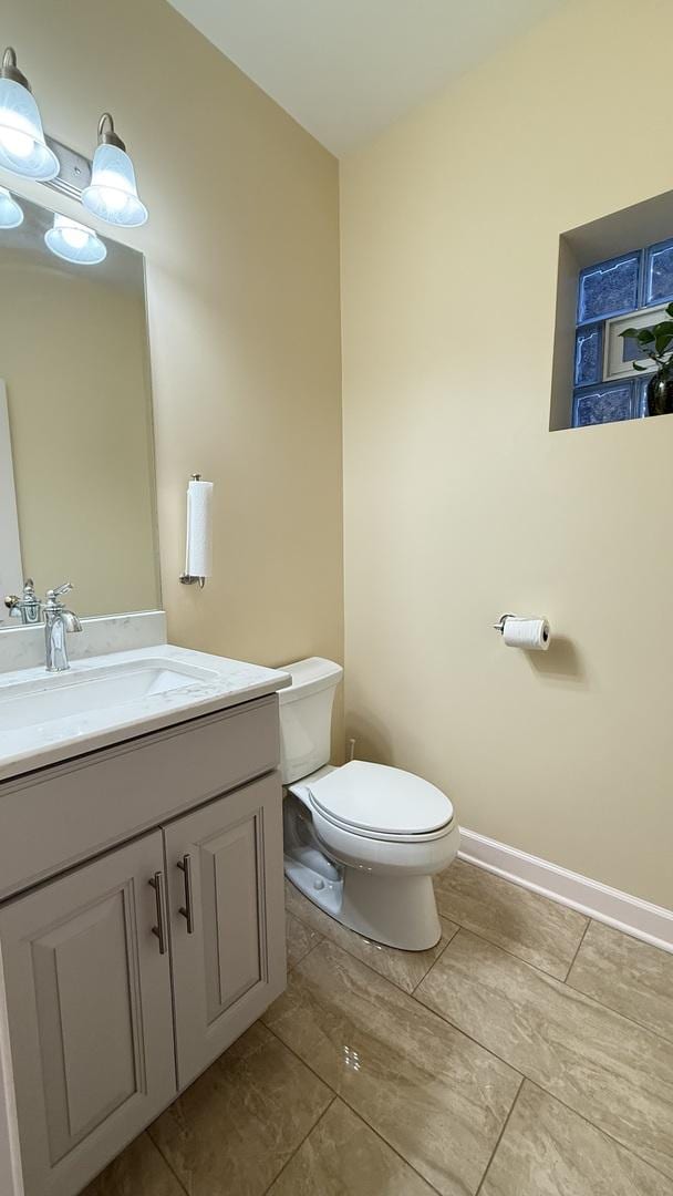 bathroom featuring baseboards, toilet, and vanity