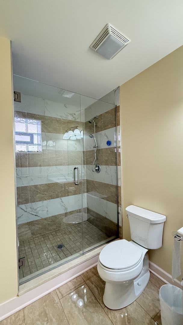 full bath featuring a shower stall, toilet, baseboards, and visible vents