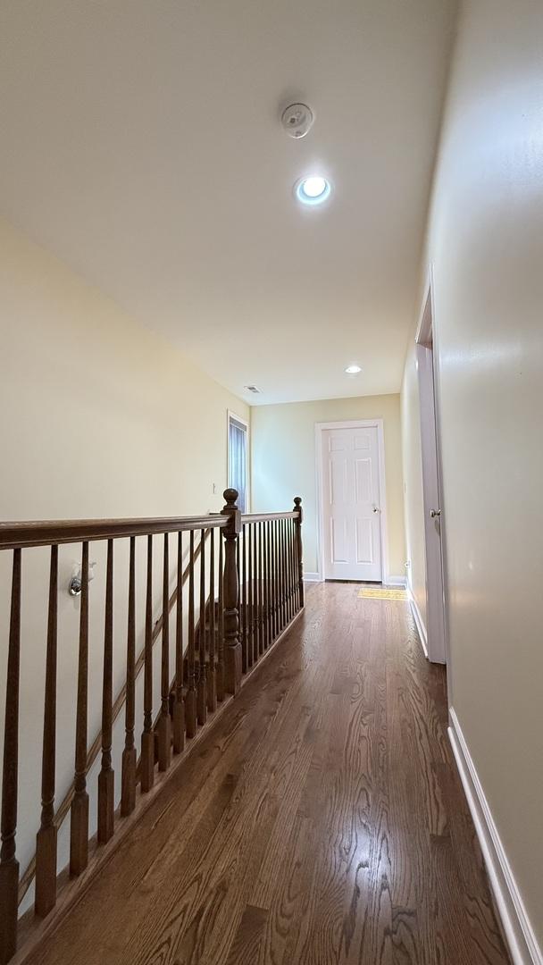 hall with recessed lighting, an upstairs landing, wood finished floors, and baseboards