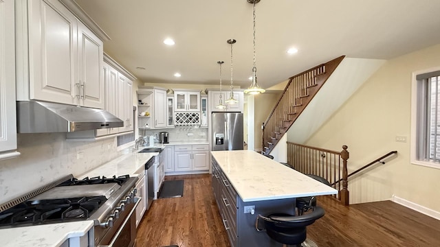 kitchen with under cabinet range hood, open shelves, a center island, appliances with stainless steel finishes, and dark wood-style flooring