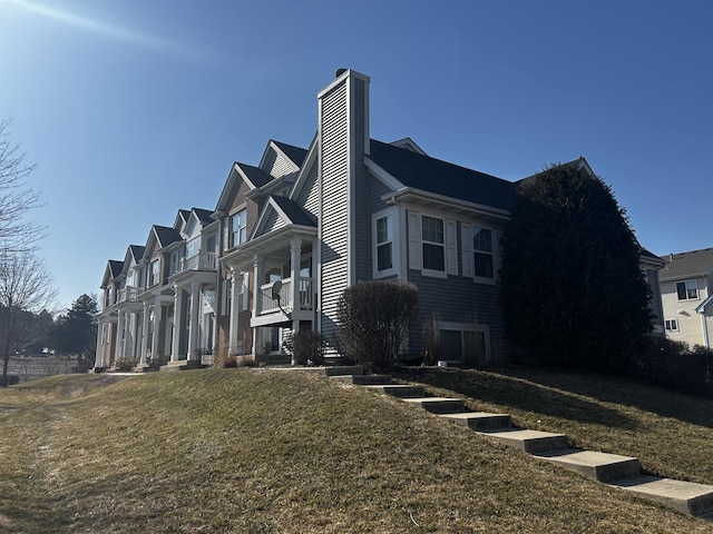 view of property exterior with a residential view, a lawn, and a chimney