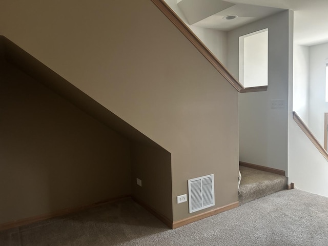 stairway featuring baseboards, visible vents, and carpet floors