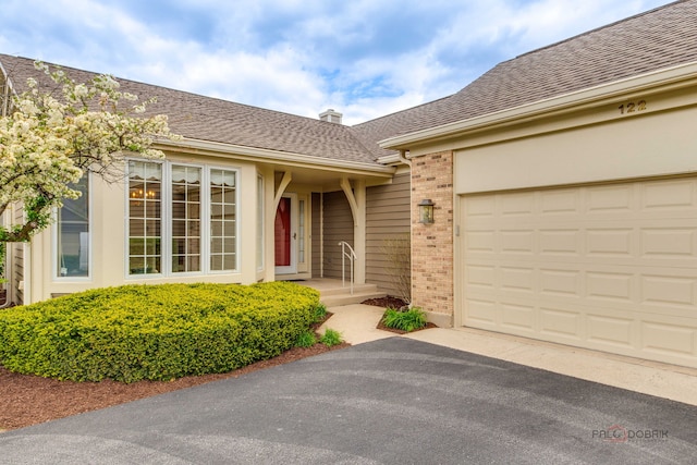 122 Kilchurn Ln, Inverness, IL 60067 - property entrance featuring brick siding, asphalt driveway, roof with shingles, an attached garage, and a chimney