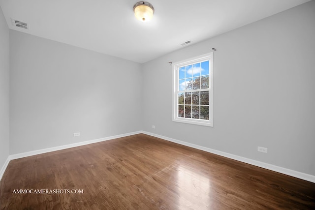 unfurnished room featuring baseboards, visible vents, and wood finished floors