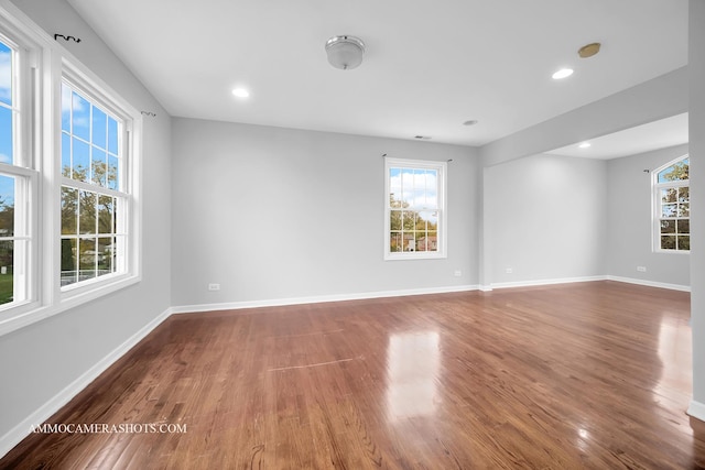 unfurnished room featuring plenty of natural light, baseboards, and wood finished floors