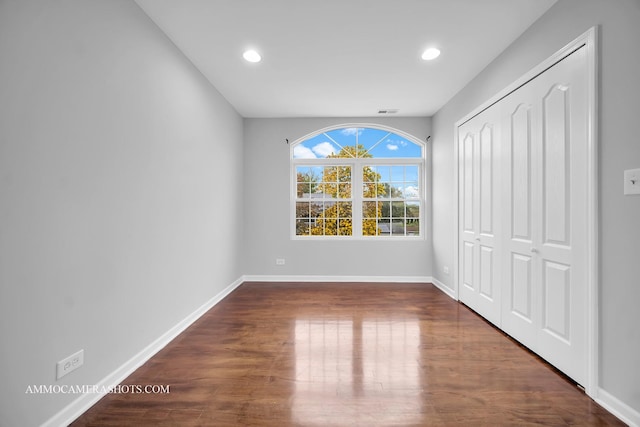 unfurnished bedroom with a closet, baseboards, wood finished floors, and recessed lighting