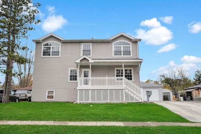 view of front of home with an outbuilding, a porch, a front yard, and a garage