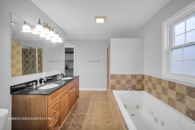 bathroom featuring a stall shower, a sink, a tub with jets, and double vanity