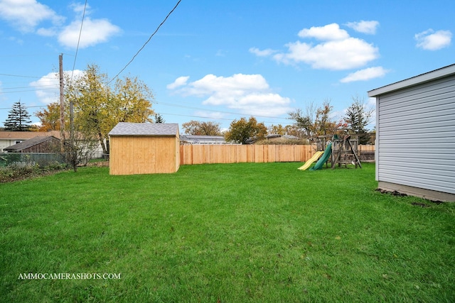 view of yard with an outbuilding, a storage unit, a playground, and a fenced backyard