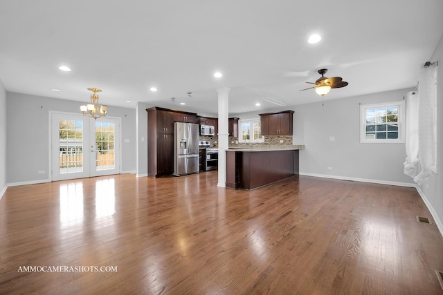 unfurnished living room with dark wood-type flooring, recessed lighting, visible vents, and ceiling fan with notable chandelier