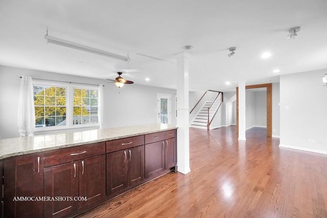 kitchen with light wood-type flooring, decorative columns, light stone counters, and recessed lighting