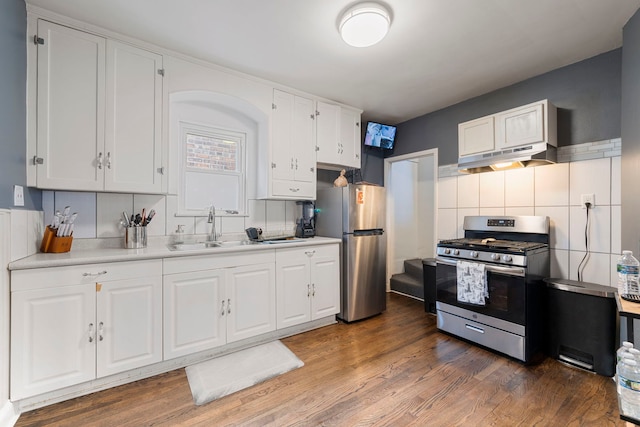 kitchen featuring under cabinet range hood, light countertops, white cabinets, stainless steel appliances, and a sink