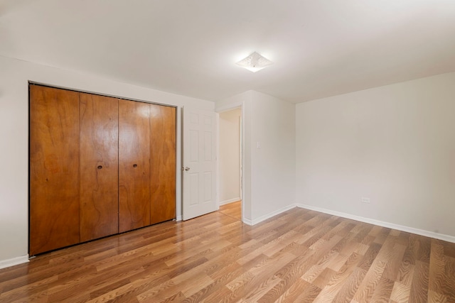 unfurnished bedroom with a closet, baseboards, and light wood-style flooring