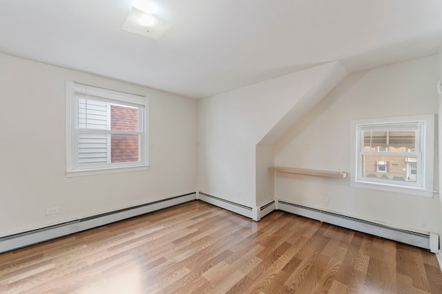 bonus room with light wood-type flooring and a baseboard radiator