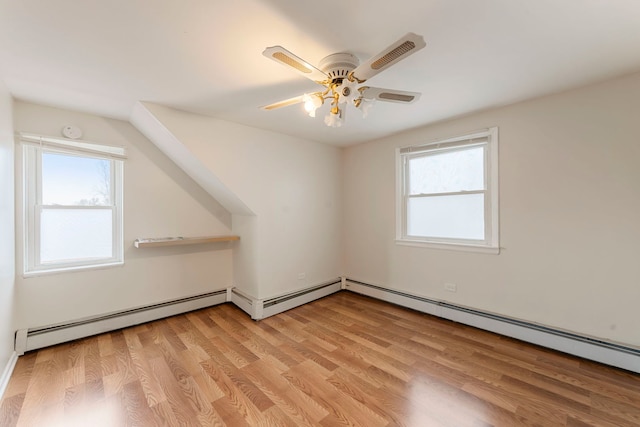 additional living space with plenty of natural light, baseboard heating, and light wood finished floors