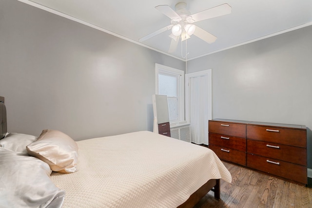 bedroom featuring wood finished floors, ornamental molding, and a ceiling fan