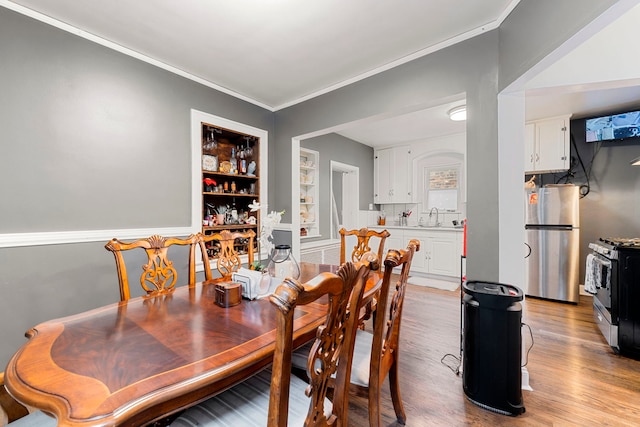 dining room featuring built in shelves, crown molding, and wood finished floors