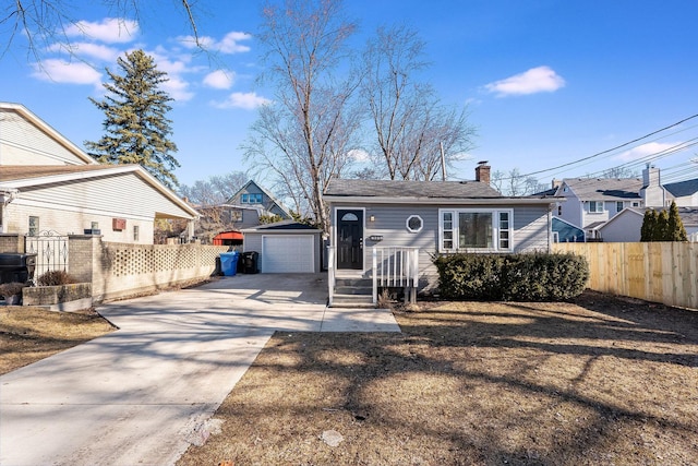 view of front of property with an outbuilding, fence, a chimney, concrete driveway, and a detached garage