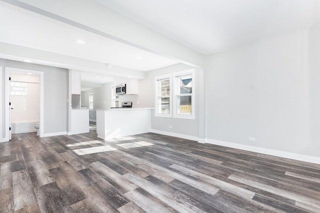 unfurnished living room with dark wood finished floors, beam ceiling, recessed lighting, and baseboards