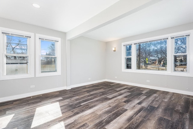 spare room featuring dark wood finished floors, visible vents, beam ceiling, and baseboards