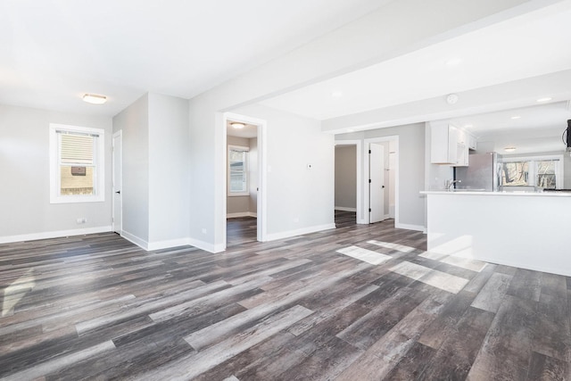 unfurnished living room featuring recessed lighting, baseboards, dark wood-type flooring, and a healthy amount of sunlight