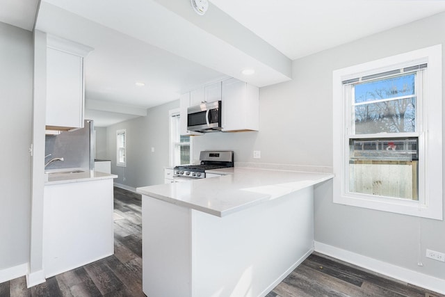 kitchen featuring white cabinets, appliances with stainless steel finishes, light countertops, and dark wood-type flooring