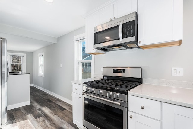 kitchen with baseboards, light stone countertops, dark wood finished floors, stainless steel appliances, and white cabinetry