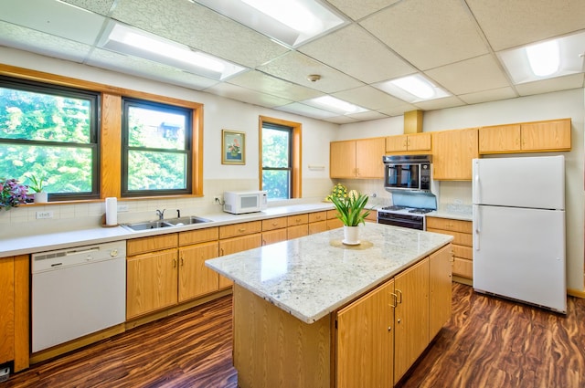 kitchen featuring a sink, backsplash, a kitchen island, white appliances, and dark wood-style flooring