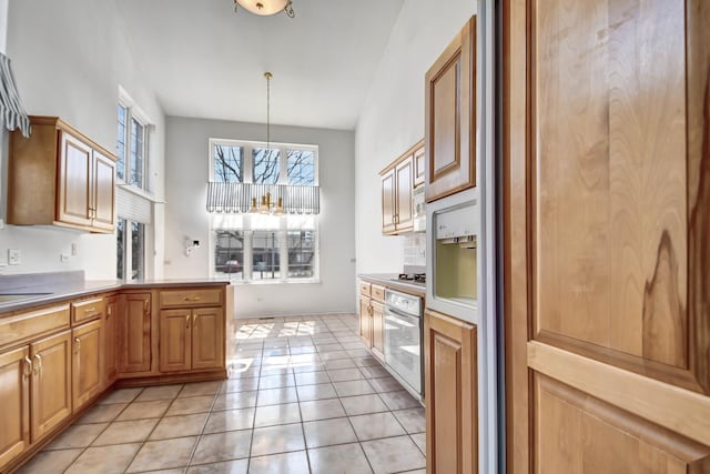 kitchen with light tile patterned floors, stainless steel appliances, a peninsula, and decorative light fixtures