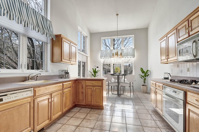 kitchen featuring paneled dishwasher, stainless steel gas cooktop, light tile patterned flooring, a sink, and white oven