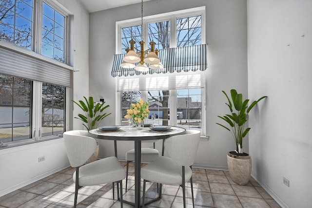 tiled dining area featuring plenty of natural light, a towering ceiling, and a chandelier