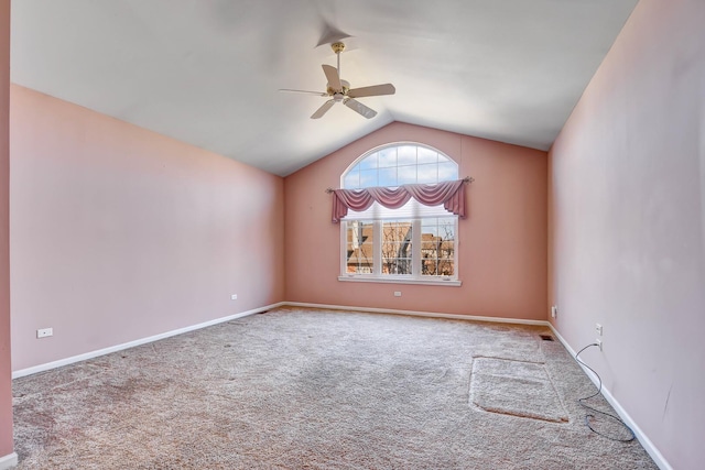 carpeted spare room featuring vaulted ceiling, baseboards, and ceiling fan