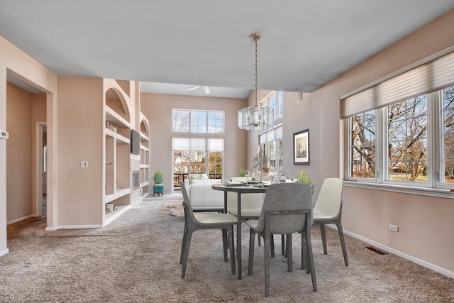 carpeted dining room featuring a notable chandelier, visible vents, and baseboards