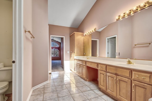 bathroom featuring tile patterned flooring, toilet, lofted ceiling, double vanity, and a sink