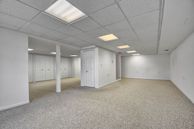 finished below grade area with carpet flooring, a paneled ceiling, and baseboards