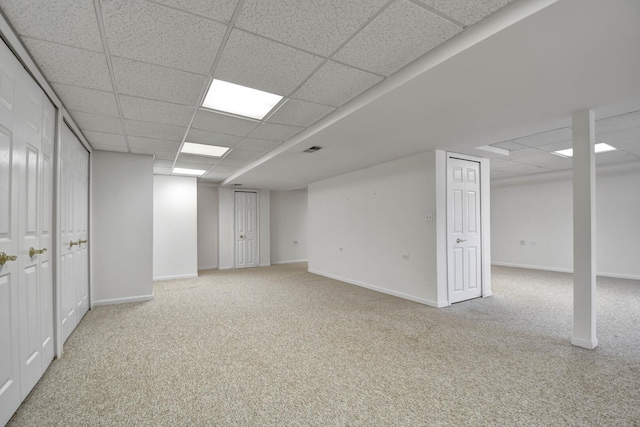 finished below grade area with a paneled ceiling, carpet floors, and visible vents