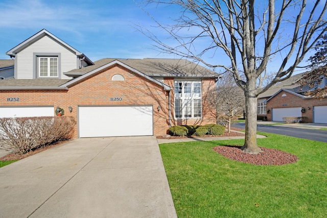 traditional-style house featuring a front lawn, driveway, an attached garage, a shingled roof, and brick siding