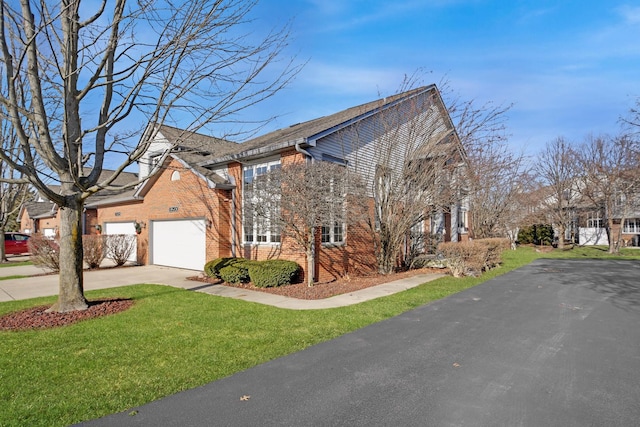 view of side of home featuring brick siding, a lawn, and driveway