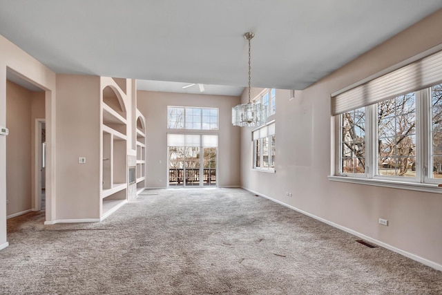 unfurnished dining area with a notable chandelier, carpet flooring, baseboards, and visible vents