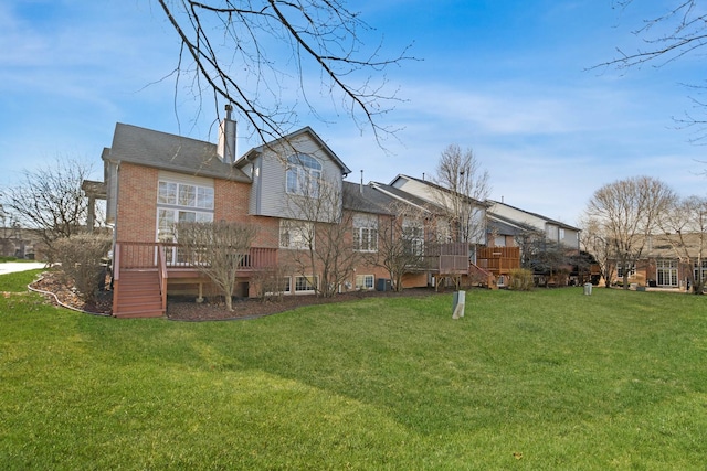 rear view of property with a deck, a yard, brick siding, and a chimney