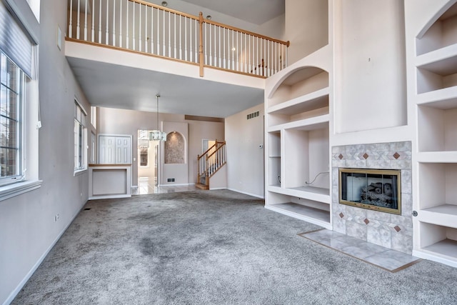 unfurnished living room with carpet floors, a high ceiling, and built in shelves