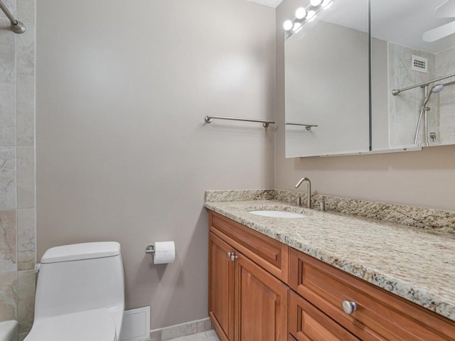 bathroom with vanity, toilet, ceiling fan, and tiled shower