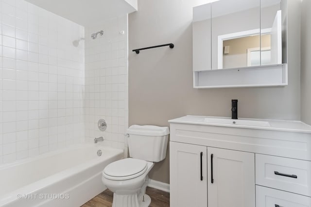 bathroom featuring vanity, washtub / shower combination, wood finished floors, baseboards, and toilet