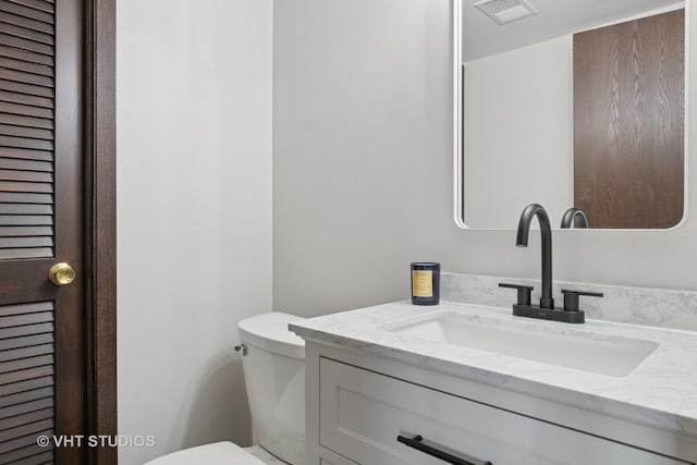 bathroom featuring visible vents, toilet, and vanity