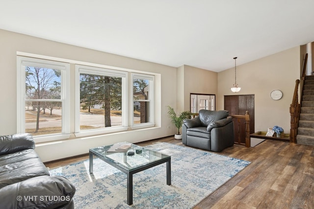 living area featuring stairs, wood finished floors, a healthy amount of sunlight, and lofted ceiling